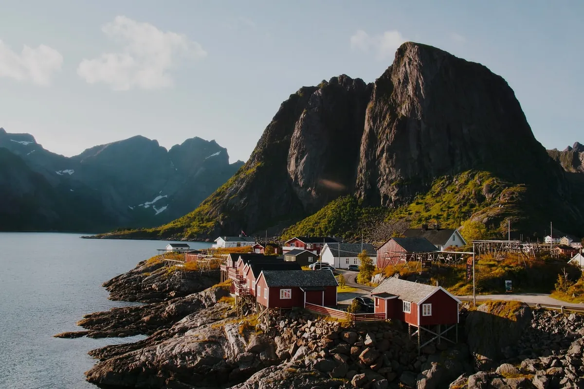 Red fishing cabins below steep peaks in the Lofoten Islands